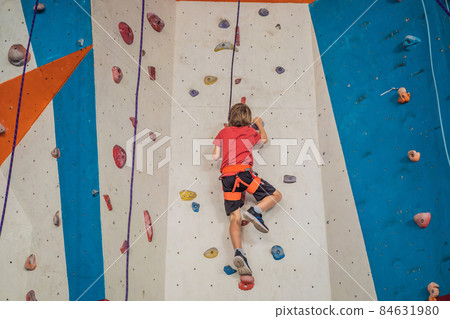 Boy at the climbing wall without a helmet, danger at the climbing wall 84631980