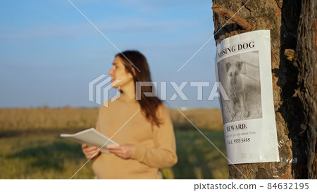 Nervous lady with flyers in park focus on missing dog poster Nervous lady with flyers in park focus on missing dog poster 84632195
