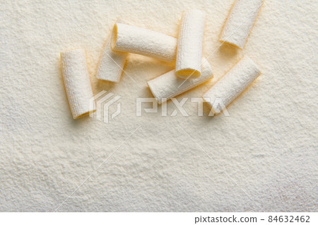 Top view of whole grain Italian pasta sprinkled with flour on a flat surface with copy ad space 84632462