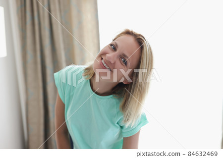 Happy smiling blonde young woman in apartment posing on curtain 84632469