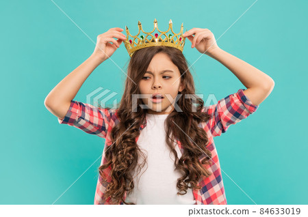 serious kid with curly hair in princess crown on blue background, smug serious kid with curly hair in princess crown on blue background, smug 84633019