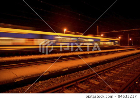 Passenger train on railroad tracks at night Blurred motion Passenger train on railroad tracks at night Blurred motion 84633217