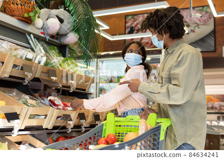 Black Millennial Couple Buying Groceries And Vegetables Shopping In Supermarket Black Millennial Couple Buying Groceries And Vegetables Shopping In Supermarket 84634241