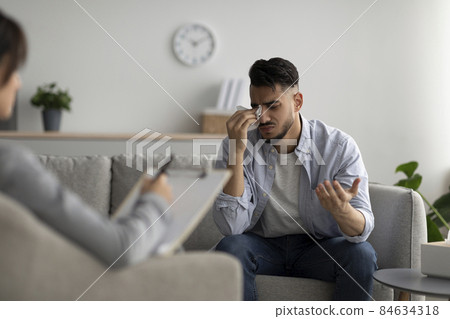 Depressed middle eastern guy crying at psychotherapist's office, seeking professional help, sharing his problems Depressed middle eastern guy crying at psychotherapist's office, seeking professional help, sharing his problems 84634318