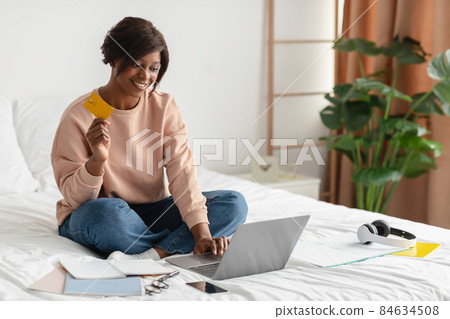 African Lady At Laptop Shopping Online In Modern Bedroom African Lady At Laptop Shopping Online In Modern Bedroom 84634508