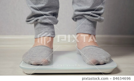 Woman stands on electronic scale to measure weight closeup Woman stands on electronic scale to measure weight closeup 84634696