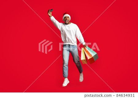 African american man Santa Claus holding purchases and credit card African american man Santa Claus holding purchases and credit card 84634931