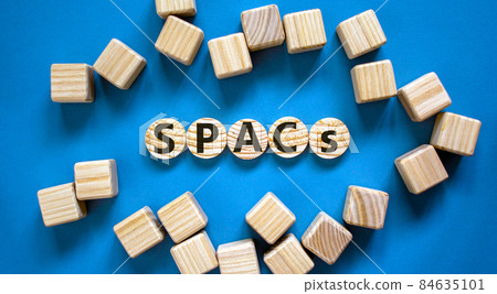 SPACs symbol. Wooden circles with words 'SPACs, special purpose acquisition companies' on beautiful blue background, copy space. Business and SPACs concept. 84635101