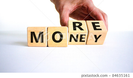 More money symbol. Businessman turns wooden cubes and changes the word 'More' to 'Money'. Beautiful white table, white background, copy space. Business and more money concept. More money symbol. Businessman turns wooden cubes and changes the word 'More' to 'Money'. Beautiful white table, white background, copy space. Business and more money concept. 84635161