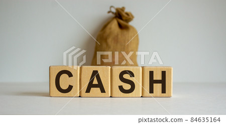 Concept word 'cash' on cubes on a beautiful wooden table. Large canvas bag. Beautiful white background. Concept word 'cash' on cubes on a beautiful wooden table. Large canvas bag. Beautiful white background. 84635164