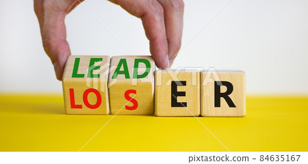 Loser or leader symbol. Businessman turns cubes and changes the word 'loser' to 'leader'. Beautiful yellow table, white background. Business and loser or leader concept. Copy space. Loser or leader symbol. Businessman turns cubes and changes the word 'loser' to 'leader'. Beautiful yellow table, white background. Business and loser or leader concept. Copy space. 84635167