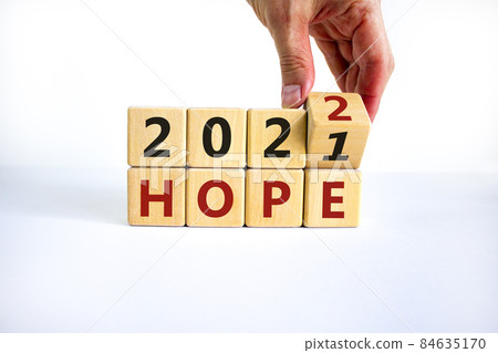 2022 hope new year symbol. Businessman turns a wooden cube and changes words 'Hope 2021' to 'Hope 2022'. Beautiful white background, copy space. Business, 2022 hope new year concept. 2022 hope new year symbol. Businessman turns a wooden cube and changes words 'Hope 2021' to 'Hope 2022'. Beautiful white background, copy space. Business, 2022 hope new year concept. 84635170