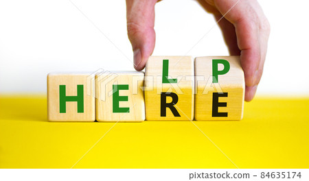 Help is here symbol. Businessman turns cubes and changes the word help to here. Beautiful white background, copy space. Business, motivational and help is here concept. Help is here symbol. Businessman turns cubes and changes the word help to here. Beautiful white background, copy space. Business, motivational and help is here concept. 84635174