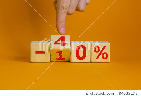 Hand turns a cube and changes the expression '-10 percent' to '-40 percent'. Beautiful orange background, copy space. Business concept. Hand turns a cube and changes the expression '-10 percent' to '-40 percent'. Beautiful orange background, copy space. Business concept. 84635175