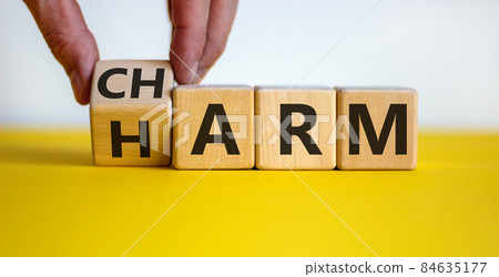 From harm to charm. Male hand turns the cube and changes word 'harm' to 'charm'. Beautiful yellow table, white background. Business and harm or charm concept. Copy space. From harm to charm. Male hand turns the cube and changes word 'harm' to 'charm'. Beautiful yellow table, white background. Business and harm or charm concept. Copy space. 84635177