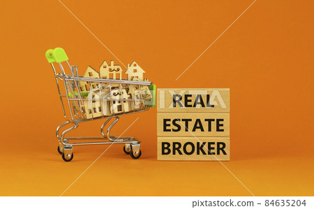 Real estate broker symbol. Wooden blocks with words 'Real estate broker' on beautiful orange background. Shopping cart with miniature wooden houses. Business, Real estate broker concept. Copy space. 84635204