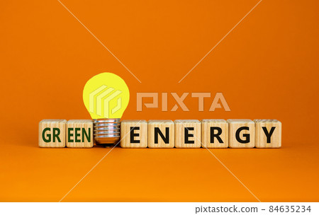 Green energy symbol. Wooden cubes with words 'green energy'. Yellow light bulb. Beautiful orange background. Business, ecological and green energy concept. Copy space. Green energy symbol. Wooden cubes with words 'green energy'. Yellow light bulb. Beautiful orange background. Business, ecological and green energy concept. Copy space. 84635234