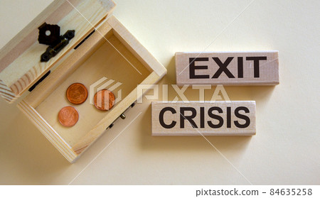 Concept words 'exit crisis' on blocks on a beautiful white background, small chest with coins. Beautiful white background, copy space. Concept words 'exit crisis' on blocks on a beautiful white background, small chest with coins. Beautiful white background, copy space. 84635258
