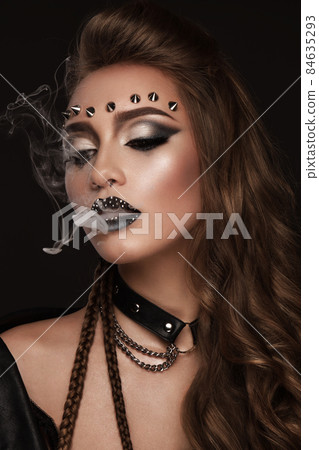 Portrait of a beautiful woman in a rock style image with creative makeup and hairstyle. Portrait of a beautiful woman in a rock style image with creative makeup and hairstyle. 84635293