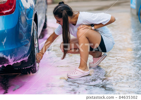Brunette with two pigtails with a sponge washes the rim Brunette with two pigtails with a sponge washes the rim 84635302
