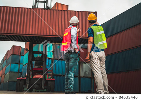 Industrial worker works with co-worker at overseas shipping container yard 84635446
