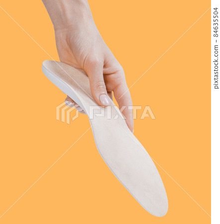 Orthopedic insole isolated on an orange background. Medical insoles. Treatment and prevention of flat feet and foot diseases. Foot care, feet comfort. Wear comfortable shoes. Flat Feet Correction. 84635504