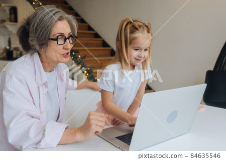 Child and granny looking at the camera with laptop Child and granny looking at the camera with laptop 84635546