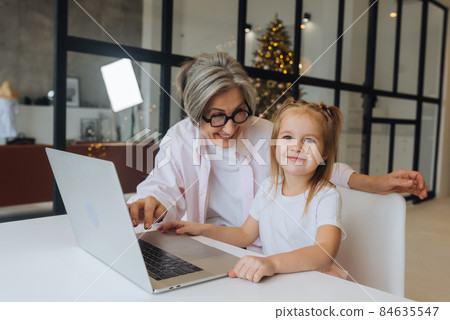 Child and granny looking at the camera with laptop Child and granny looking at the camera with laptop 84635547