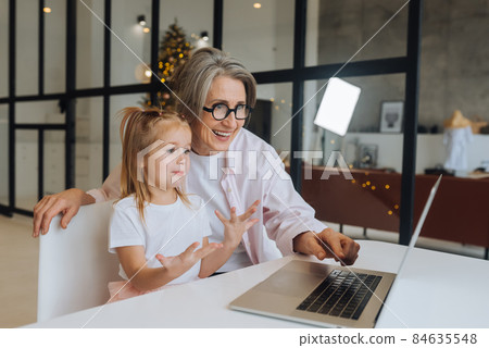 Child and granny looking at the camera with laptop Child and granny looking at the camera with laptop 84635548