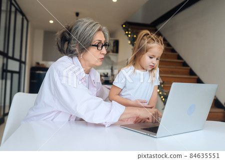Child and granny looking at the camera with laptop Child and granny looking at the camera with laptop 84635551