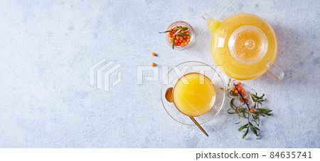 Glass teapot with sea buckthorn tea on a light background Glass teapot with sea buckthorn tea on a light background 84635741