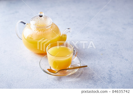 Glass teapot with sea buckthorn tea on a light background 84635742