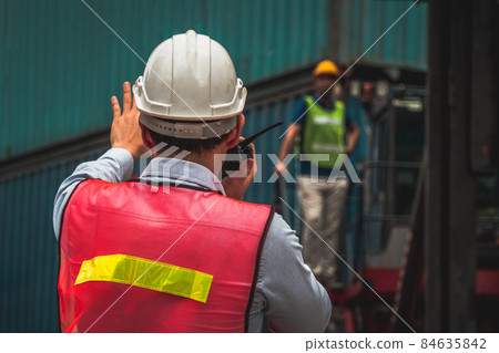 Industrial worker works with co-worker at overseas shipping container yard 84635842