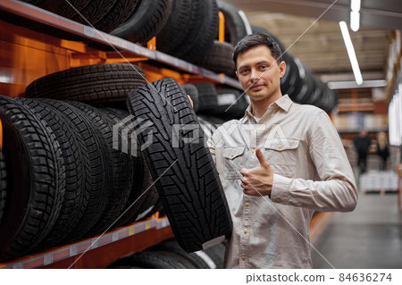 male customer taking new tires in the supermarket. male customer taking new tires in the supermarket. 84636274