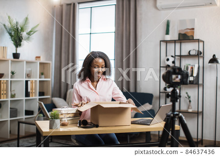 African woman doing live stream while unpacking parcel African woman doing live stream while unpacking parcel 84637436