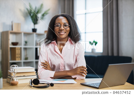 Female tutor in eyeglasses sitting at desk with books 84637452