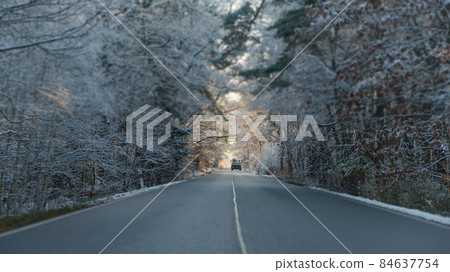 Car on the road among trees at forest covered by snow at winter frosty morning. 84637754