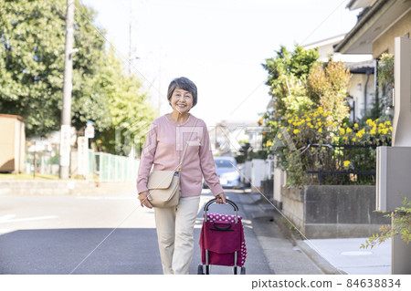 Senior woman walking with a shopping carry Senior woman walking with a shopping carry 84638834