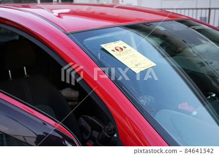 A parking violation sticker is affixed to the red car A parking violation sticker is affixed to the red car 84641342