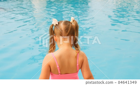 little girl 4-5 years old, dressed in a pink swimsuit, blowing soap balls in the pool on summer 84641349
