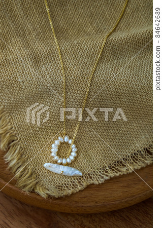 White pearl jewelry fashion photography. White pearl necklace fashion photography. Necklace presented on brown sackcloth. White pearl jewelry fashion photography. White pearl necklace fashion photography. Necklace presented on brown sackcloth. 84642689