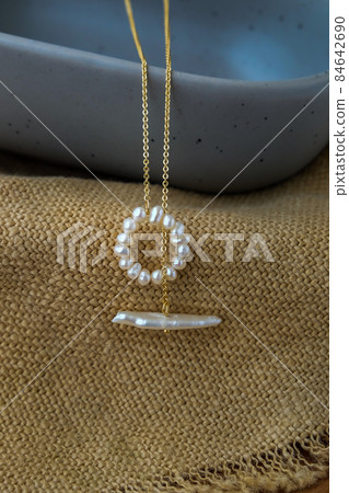 White pearl jewelry fashion photography. White pearl necklace fashion photography. Necklace presented on brown sackcloth. 84642690