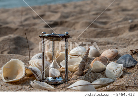 Hourglass and shells in sand on the beach and copy space. 84643438
