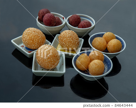 Fried Sweet Potato Balls with sesame with Deep fried purple and yellow sweet potato balls (Quail candy eggs) on black table. Fried Sweet Potato Balls with sesame with Deep fried purple and yellow sweet potato balls (Quail candy eggs) on black table. 84643444