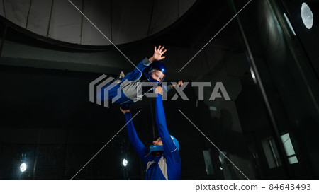 A man teaches a boy to fly in a wind tunnel. A man teaches a boy to fly in a wind tunnel. 84643493