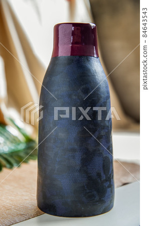 Blue and Crimson handmade ceramic vase on white textured table cloth. Blue and Crimson handmade ceramic vase on white textured table cloth. 84643543