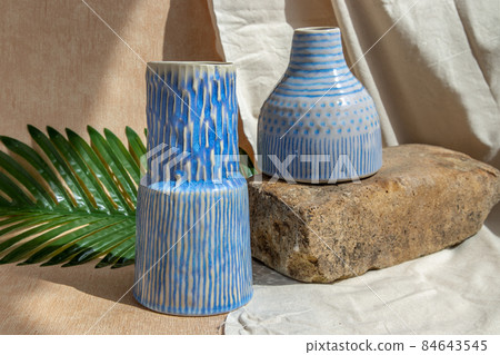 Two white and blue handmade ceramic vases on white textured table cloth. Two white and blue handmade ceramic vases on white textured table cloth. 84643545