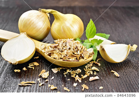 Onion flakes in spoon on dark board 84643896