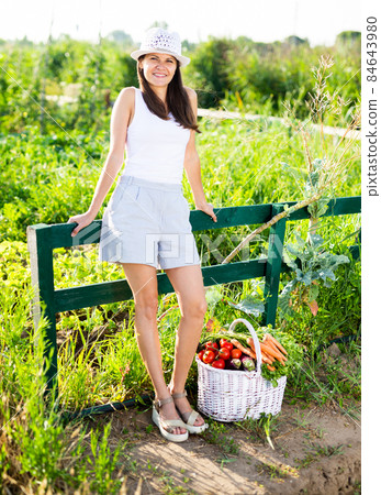 Woman posing in garden with harvested vegetables 84643980