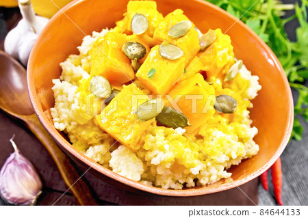 Porridge millet with spicy pumpkin in clay bowl on dark board Porridge millet with spicy pumpkin in clay bowl on dark board 84644133